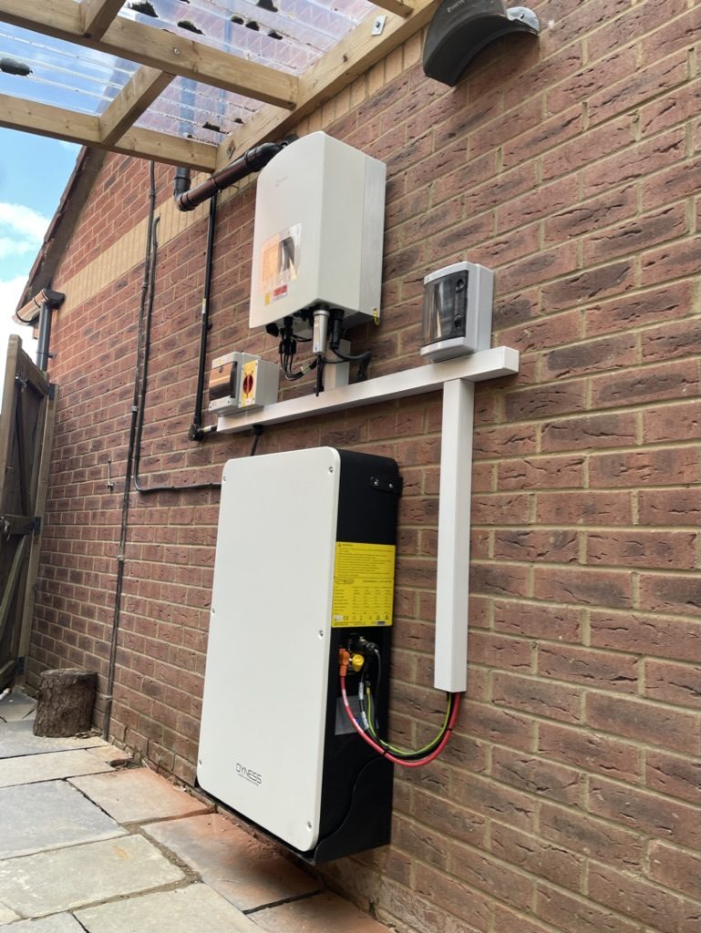 A neatly installed home battery and inverter on a brick wall