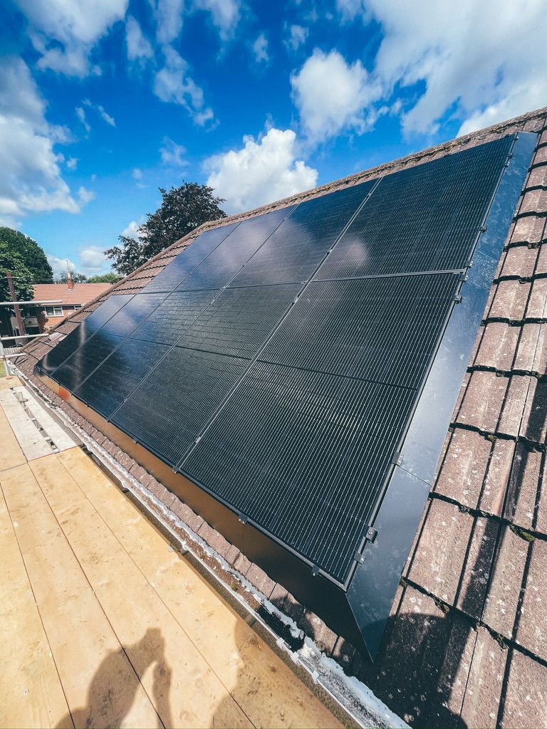 A finished all-black solar array on a tiled roof under a blue sky